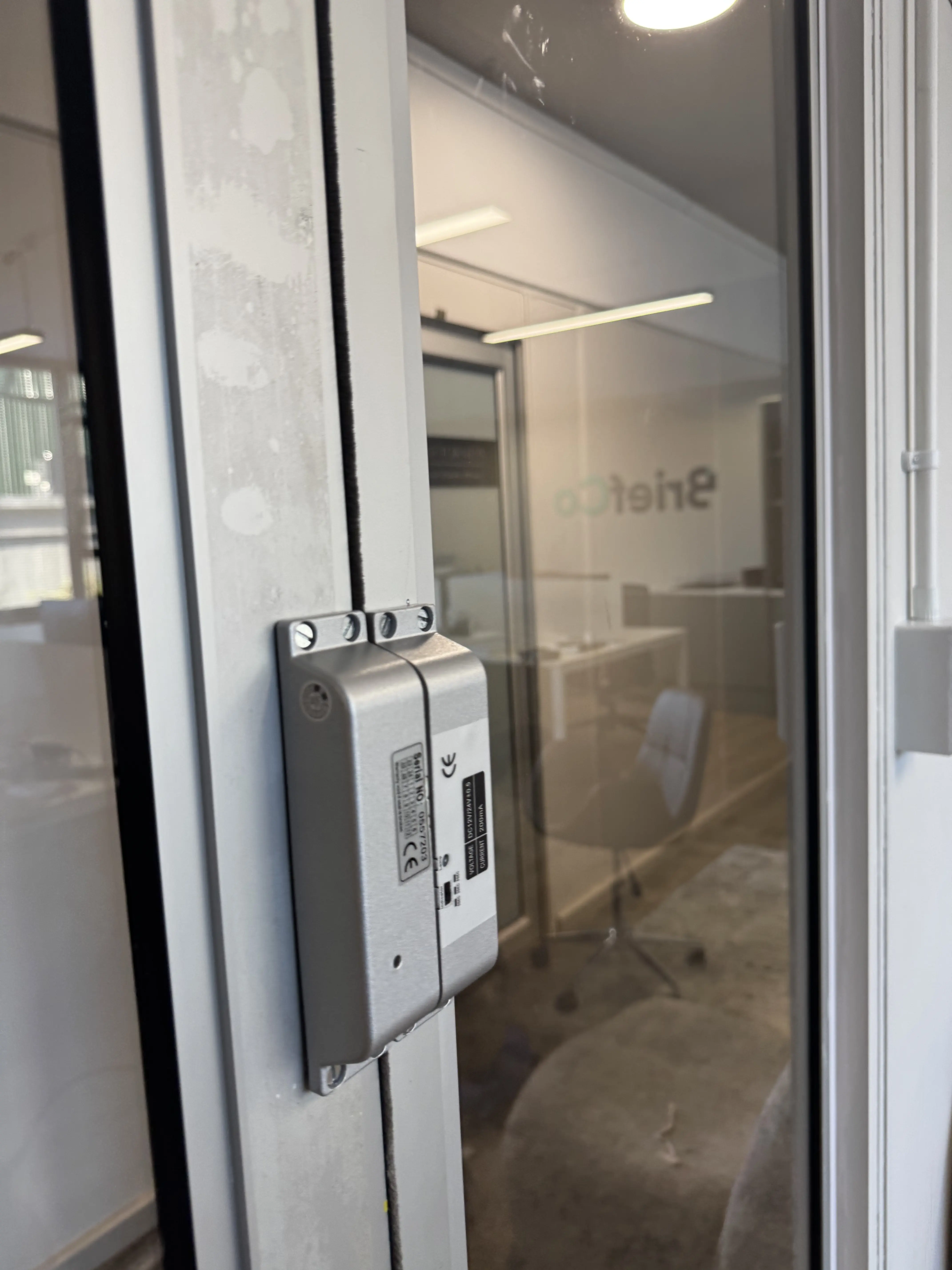 Electronic door strike lock mounted on a glass office door frame